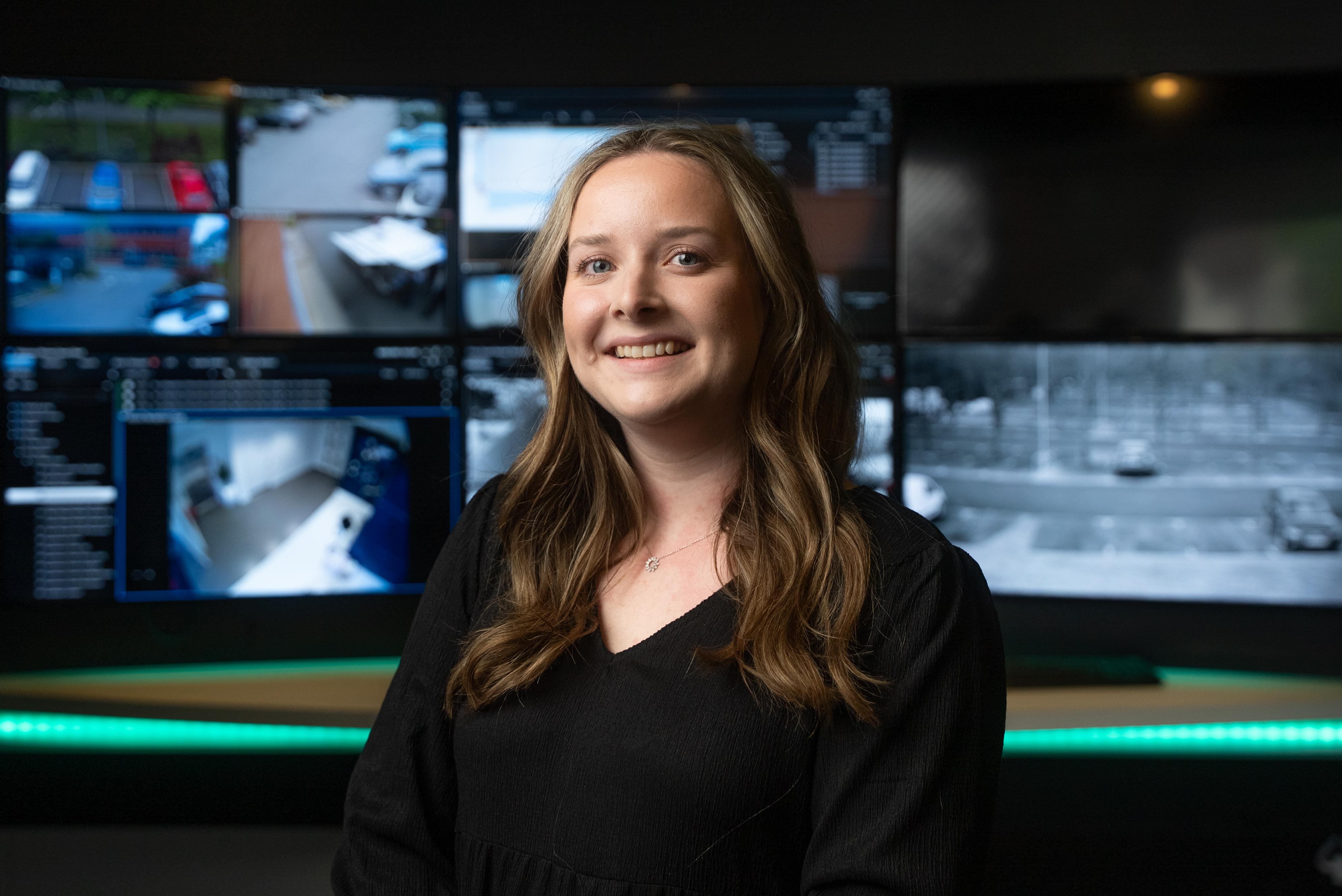 Smiling woman in front of digital screens.
